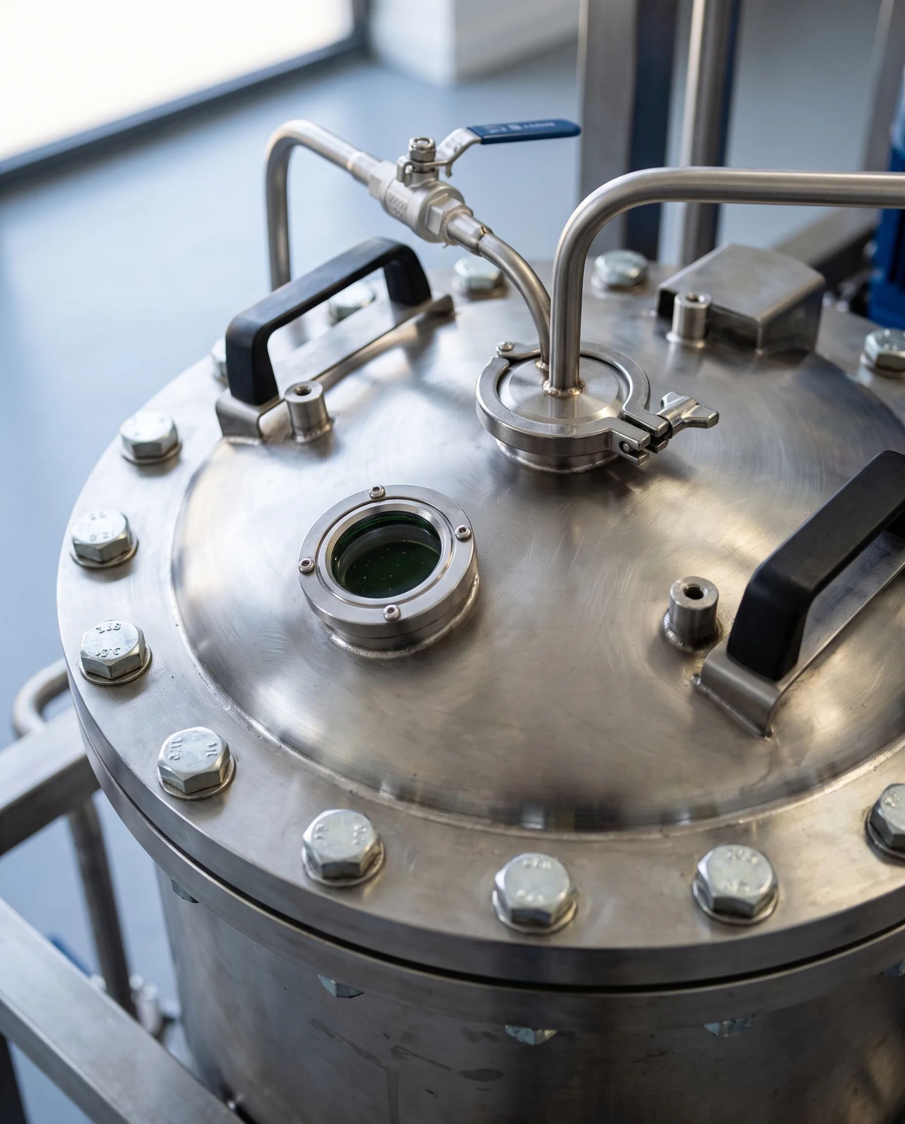 Bolted lid of a stainless steel vessel with a sight glass